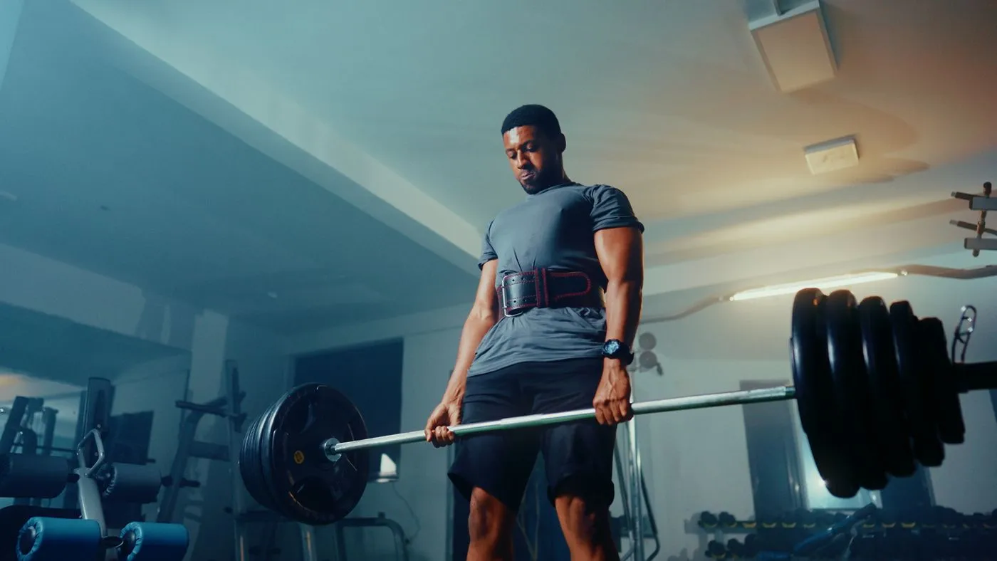 Man performing a barbell deadlift in a gym
