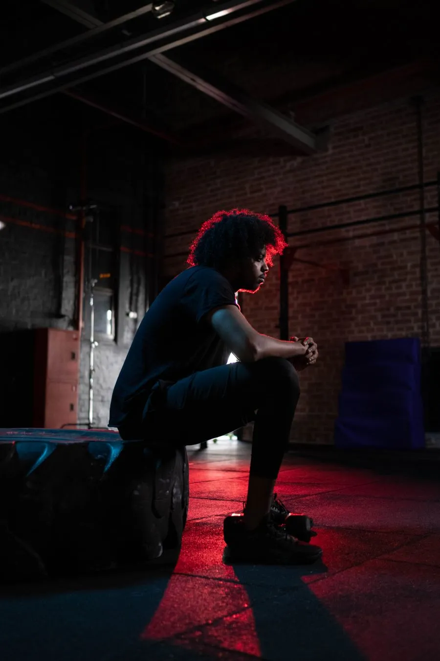 Man seated in a red-lit gym